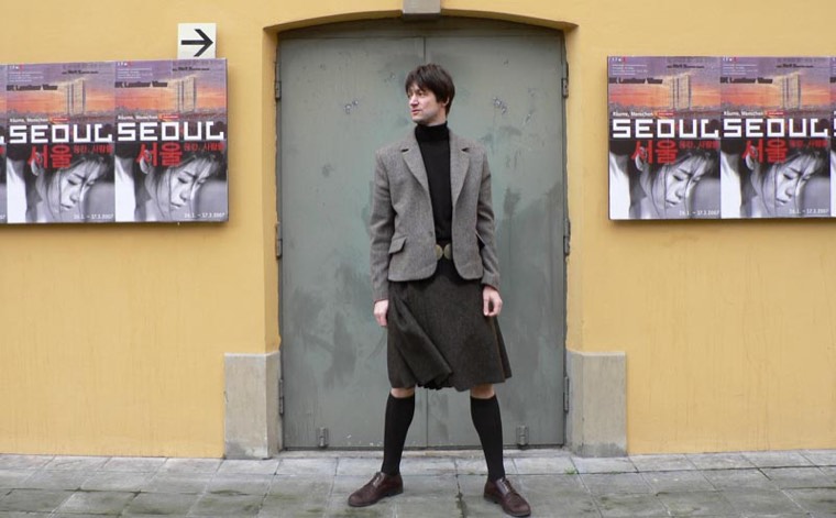 Herr im Kilt mit Tweedjacke vor gelber Wand